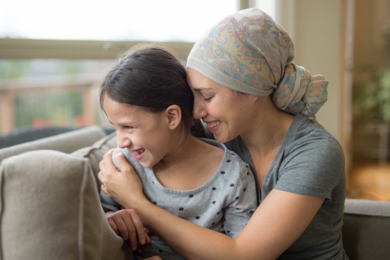 Mother in headscarf hugging daughter on couch