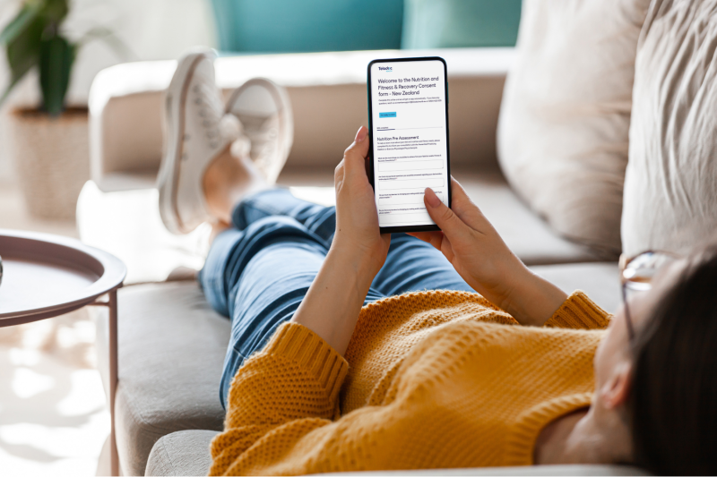A woman holding her smartphone in hands lying on a couch