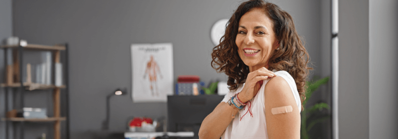 A woman with a band-aid on her shoulder smiling.