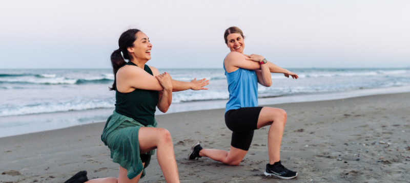 Two happy-looking women working out on the beach.