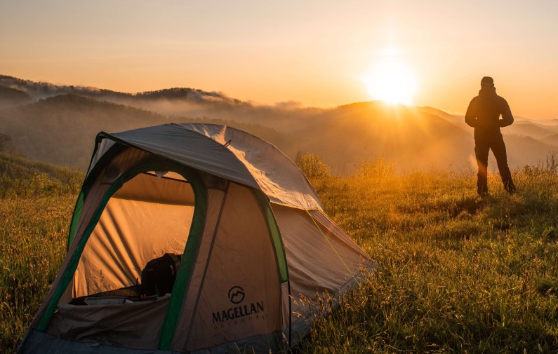 person camping in the mountains watching a golden sunset